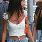 Two women walking together on a street, one in a white top and blue jeans, the other in a colorful graphic t-shirt and jeans.