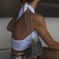 Woman in a white bikini top and sequin shorts sitting on a white surface.