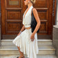 Woman in a white outfit standing on steps in front of a wooden door.
