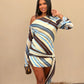 Woman wearing a striped dress posing against a beige wall.